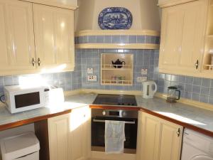 a kitchen with white cabinets and a stove and a microwave at Stouts Court Apartment in Lerwick