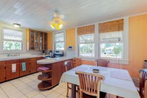 cocina con mesa, sillas y ventanas en Hamakua Hale Ohana Country Retreat en Papaikou