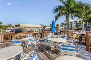 a deck with tables and chairs and palm trees at Ocean Breeze & Santa Maria Condos in Fort Myers Beach