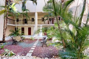 a courtyard of a building with a bench and palm trees at Ocean Breeze & Santa Maria Condos in Fort Myers Beach