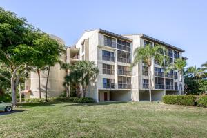 an apartment building with palm trees and a yard at Ocean Breeze & Santa Maria Condos in Fort Myers Beach