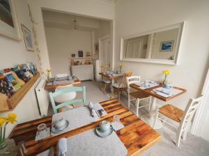 a living room with tables and chairs and a kitchen at Cowrie Guest House in Berwick-Upon-Tweed