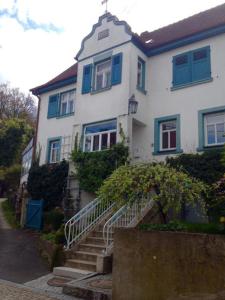 a white house with blue windows and stairs at maison milabee in Altenkunstadt