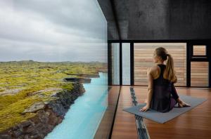 
a woman standing on a balcony talking on a cell phone at The Retreat at Blue Lagoon Iceland in Grindavík
