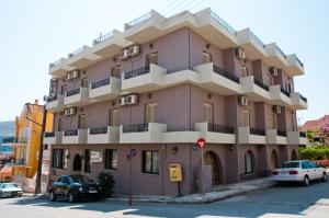 a pink building with cars parked in front of it at Argostoli Hotel in Argostoli