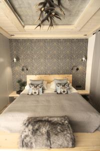 een slaapkamer met een groot bed met een grijze muur bij Domek Koliba pod Smrekami in Zakopane