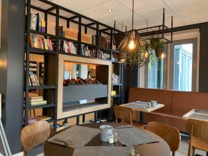 a restaurant with tables and a shelf of books at Hotel In den Brouwery in Domburg