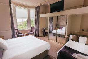 a hotel room with two beds and a mirror at Braid Hills Hotel in Edinburgh