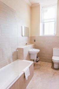 a white toilet sitting next to a bath tub in a bathroom at Best Western Edinburgh South Braid Hills Hotel in Edinburgh