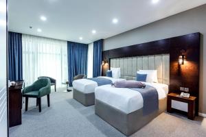a hotel room with two beds and a desk at Parallel Hotel in Baku