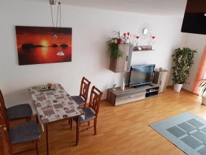 a living room with a table and a television at Am Park 2 in Wendtorf