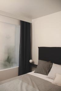 a bedroom with a bed with a black headboard and a window at Joie Paris TOUR EIFFEL in Paris