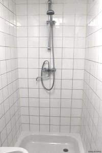a shower in a white tiled bathroom with a sink at New Ocean Paradise Hotel in Rotterdam