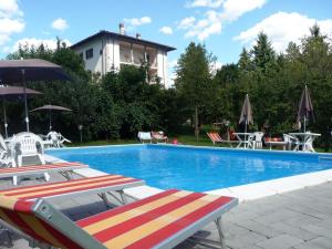 a swimming pool with chairs and tables and a building at Agriturismo La Palazzina in Castelnuovo di Garfagnana