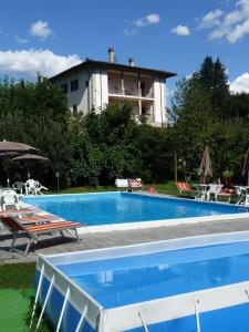 a swimming pool with chairs and a building in the background at Agriturismo La Palazzina in Castelnuovo di Garfagnana