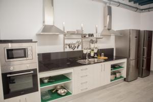 a kitchen with white cabinets and stainless steel appliances at Vivian's Guest House Auto Check-in in Jerez de la Frontera