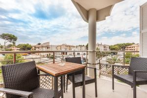 un patio con tavolo e sedie in legno sul balcone. di APARTAMENTO EL ROJO a Can Picafort