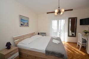 Un dormitorio con una gran cama blanca y una mesa en Guesthouse Kamen Kuća, en Podstrana