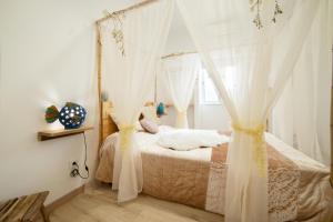a bedroom with a bed with curtains and a window at O Quintal Guesthouse in Carvoeiro