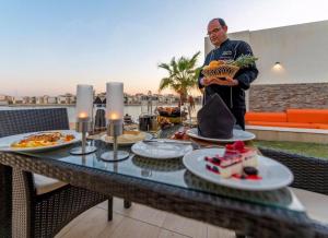 a man standing on a balcony with a table of food at Tamara Beach Resort, Al Khobar Half Moon Bay-"Families Only" in Half Moon Bay