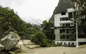 a building next to a building with a mountain at Hotel Retama Machupicchu in Machu Picchu