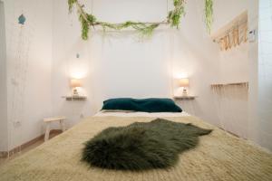 a white room with a bed with a furry rug on it at O Quintal Guesthouse in Carvoeiro