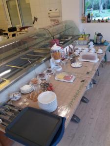 - une longue table dans une cuisine avec des assiettes et de la vaisselle dans l'établissement Anessis, à Sarakiniko
