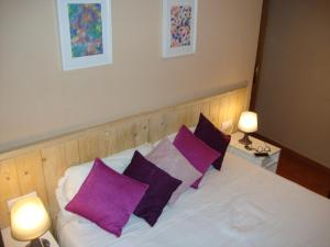 una camera da letto con un letto bianco con cuscini viola di Balcón curva de Estafeta - Centro a Pamplona