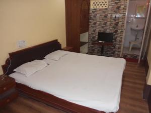 a bedroom with a large bed with white sheets at HOTEL NEELKAMAL in Indore