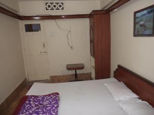 a small bedroom with a bed and a chair at HOTEL NEELKAMAL in Indore