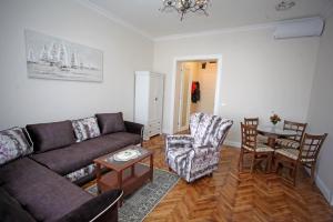 City Center Belgrade Queen Apartment Skadarlija في بلغراد: غرفة معيشة مع أريكة وطاولة وكراسي