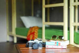 eine Kamera auf einem Tisch mit Büchern und Brillen in der Unterkunft Non La Mer Hostel - Bed & Yoga in Ko Lanta