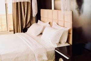 a bed with white sheets and pillows next to a window at Landmark Mbezi Beach Resort in Dar es Salaam +29 photos