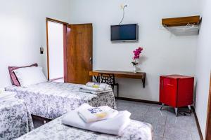 a room with two beds and a desk and a tv at Pousada Paraiso in Guanambi