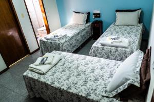 a room with three beds with towels on them at Pousada Paraiso in Guanambi