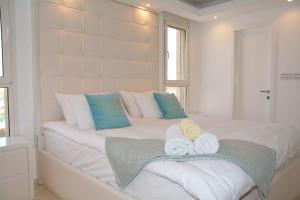 ein Schlafzimmer mit einem weißen Bett und Handtüchern darauf in der Unterkunft Renovated 3 Bedroom - Residence with Pool next the Beach in Eilat