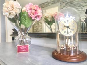 eine Uhr auf einem Tisch mit Vasen und Blumen in der Unterkunft B&B La coccola in Lainate