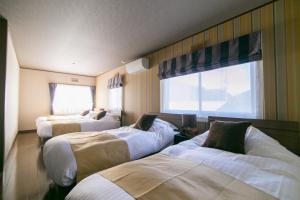 a hotel room with three beds and a window at villa yawaragi in Fujikawaguchiko