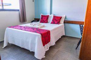 a small bedroom with a bed with red pillows at Pousada Paraiso in Guanambi