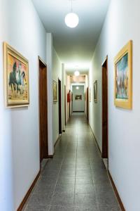 a long hallway with paintings on the walls at Pousada Paraiso in Guanambi