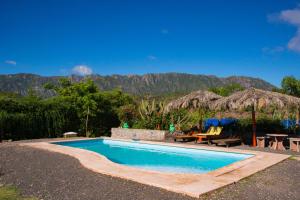 einen Pool mit einem Tisch, Stühlen und Bergen in der Unterkunft Complejo Flores Azules in Olta