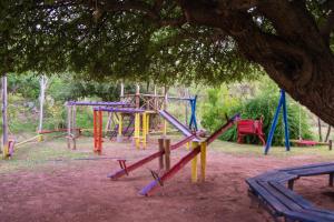 einen Spielplatz mit bunter Spielausrüstung unter einem Baum in der Unterkunft Complejo Flores Azules in Olta