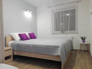 sypialnia z łóżkiem z fioletowymi poduszkami i oknem w obiekcie Apartament Marzenie 5 - Opole w mieście Opole