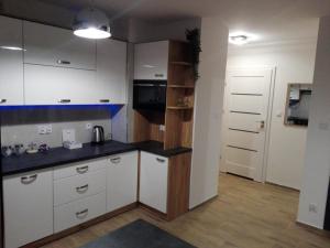 kuchnia z białymi szafkami i czarnym blatem w obiekcie Apartament Marzenie 5 - Opole w mieście Opole