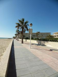einen Bürgersteig neben einem Strand mit Palmen in der Unterkunft Fantástico Apartamento 1ª Línea de Playa in Cambrils
