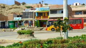 un autobús rojo y amarillo conduciendo por una calle de la ciudad en Urcia Surf House en Huanchaco