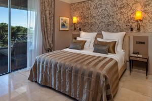 
a bedroom with a large bed and a large window at Alàbriga Hotel & Home Suites GL in S'agaro
