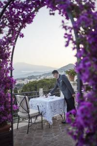a man in a suit standing at a table with a table cloth at Grand Hotel Timeo, A Belmond Hotel, Taormina in Taormina