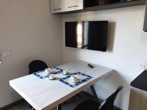 Una mesa blanca con dos tazas y platillos. en Sun Lake Apartments en Desenzano del Garda