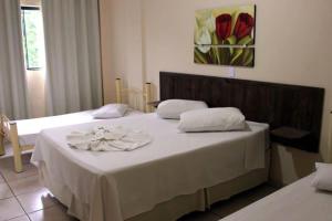een slaapkamer met 2 bedden en witte lakens bij Hotel Santiago in Lindóia